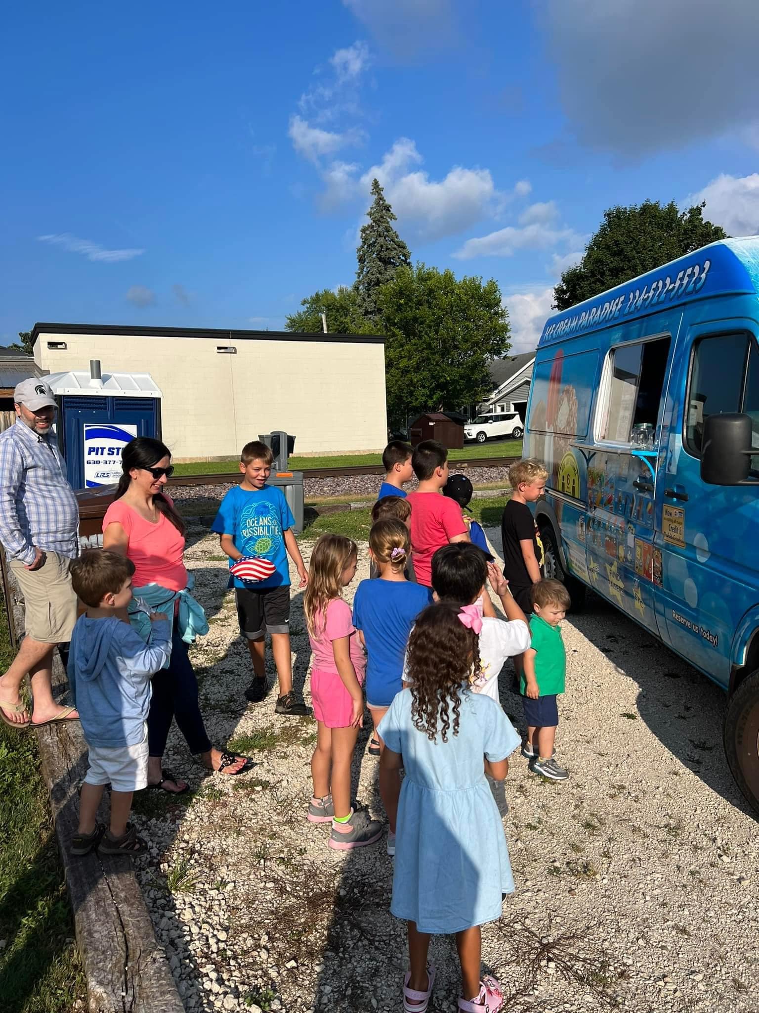 Group of excited children in red uniforms lined up at Ice Cream Paradise truck